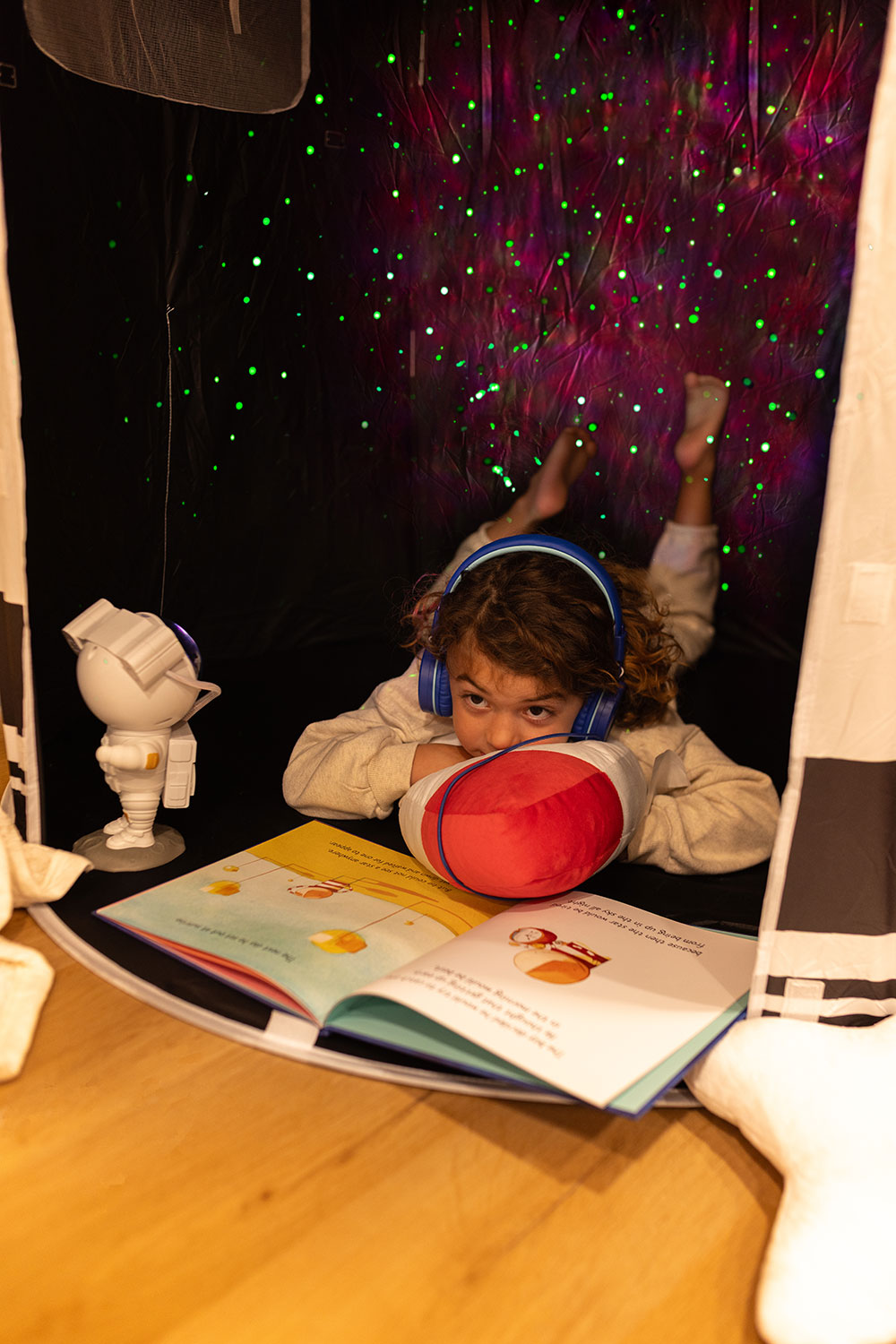 Boy reading with astronaut light projector on