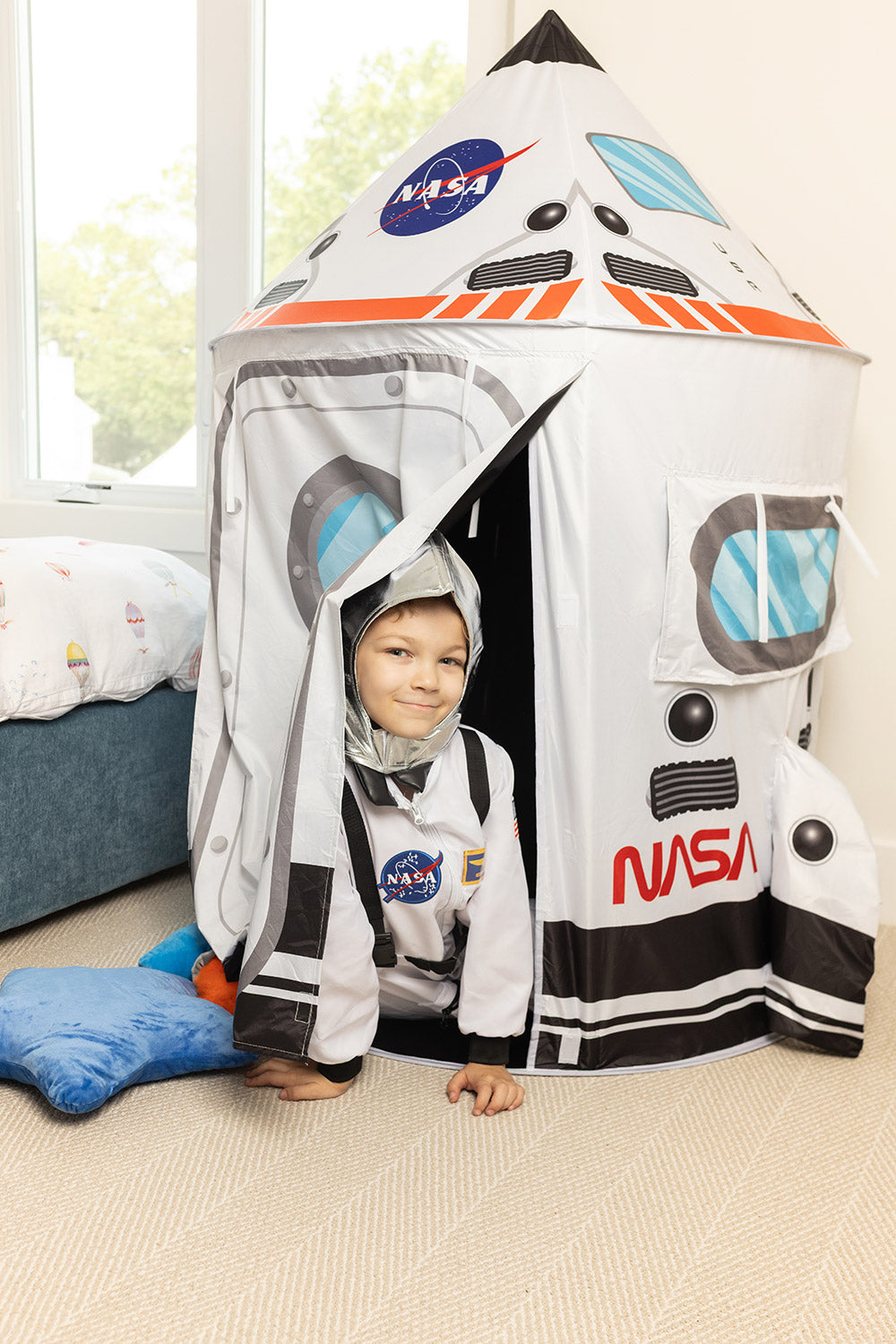 boy dressed as astronaut peeking out from space tent